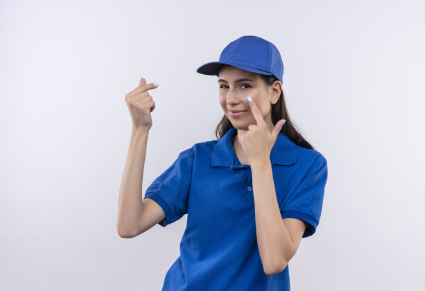 等待穿着蓝色制服 戴着帽子的年轻送货员用手指指着眼睛等着付款交货帽子年轻