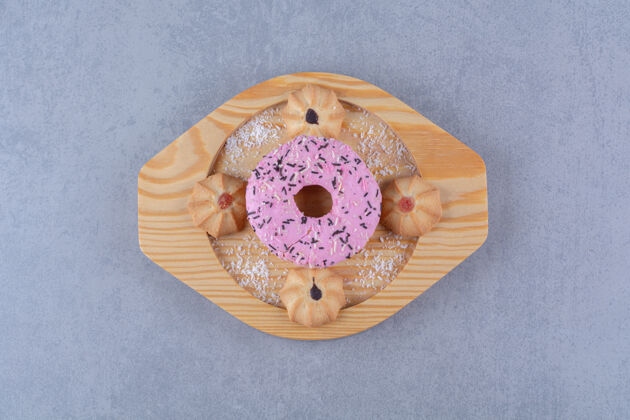 圆的一盘美味的粉红色甜甜圈配甜饼木头好吃的吃的