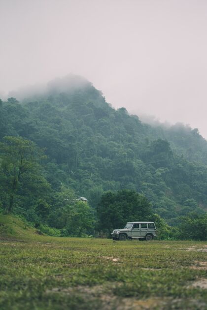 自然垂直拍摄的山上覆盖着绿色植物和一辆汽车蓝色森林多云