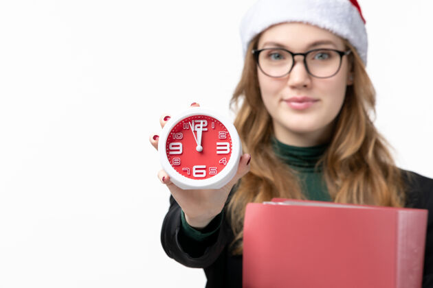 圣诞节正面图年轻女性拿着时钟和文件在白墙上上大学课本课程漂亮文件