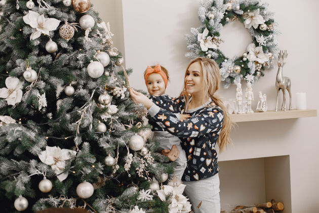 孩子美丽的母亲带着孩子一家人在圣诞气氛中人们戴着圣诞树圣诞室内生活