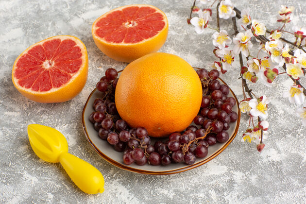 维生素正面图：白色表面上有葡萄的新鲜柚子环柑橘健康戒指