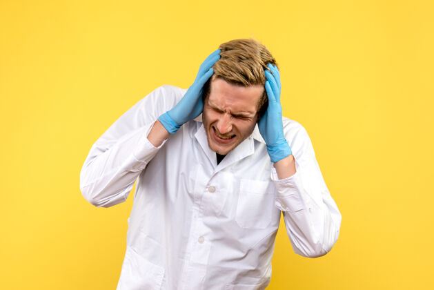 人正面图黄色背景上头痛的男医生-人类情感医生男性医生成人观点