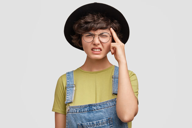 眼镜失意的年轻女学生试图记住一些事情帽子华丽姿势