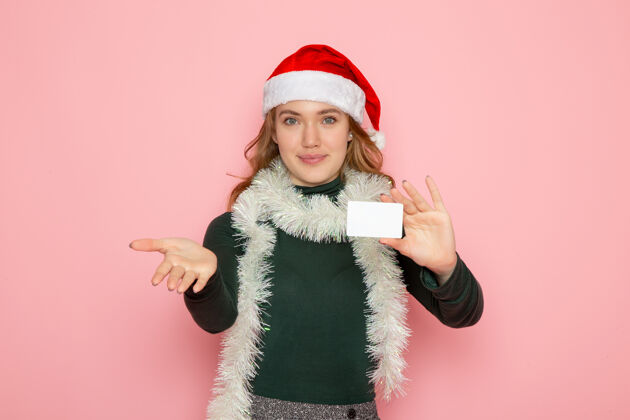 颜色正面图年轻女性手持银行卡在粉色墙面上的彩色模特节日圣诞新年感慨银行羽毛蟒蛇看法
