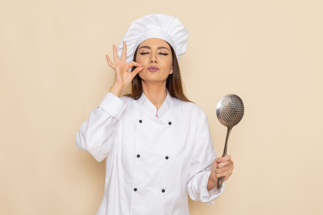 女身穿白色厨师服的年轻女厨师正拿着大银勺站在白墙上医生厨房医疗