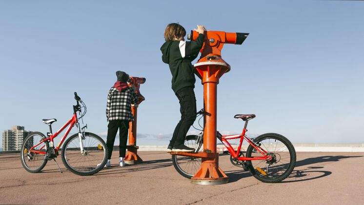 自行车男孩骑着自行车透过望远镜看户外水平爱好活动