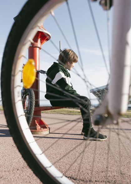 活跃坐在望远镜旁边的男孩骑着自行车户外爱好休闲