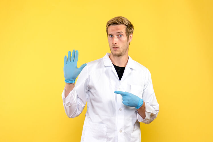 医学前视图男性医生在黄色背景上展示他的手掌健康科维德-大流行医疗听诊器视图医生
