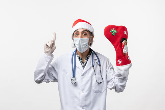 冠状病毒正面图白色办公桌上戴着大节日袜子的男医生柯维德圣诞病毒男医生男人袜子