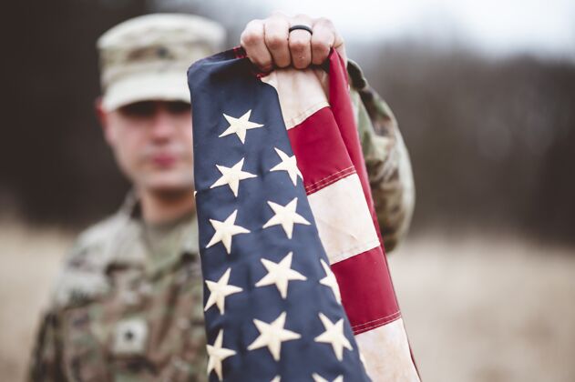 焦点一名美国士兵举着美国国旗靠近镜头的选择性聚焦镜头战争男性战士