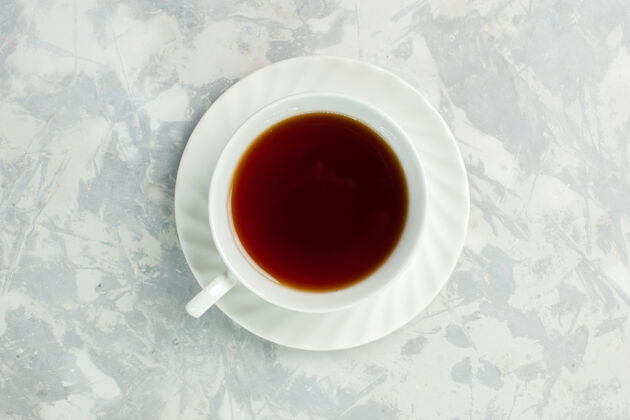 早晨在浅白色的桌子上俯瞰一杯热茶药草茶食品早餐