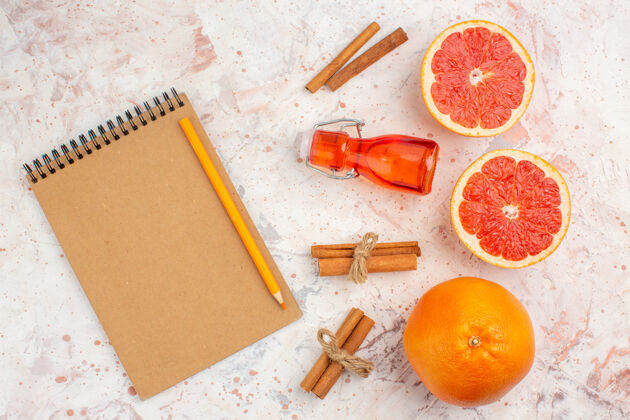 肉桂俯视图切割柚子肉桂棒瓶子笔记本黄色铅笔裸体表面棒顶部柑橘