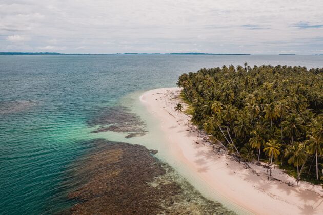岛屿鸟瞰一个美丽的热带海滩与白色沙滩和绿松石碧水在印度尼西亚云树地平线