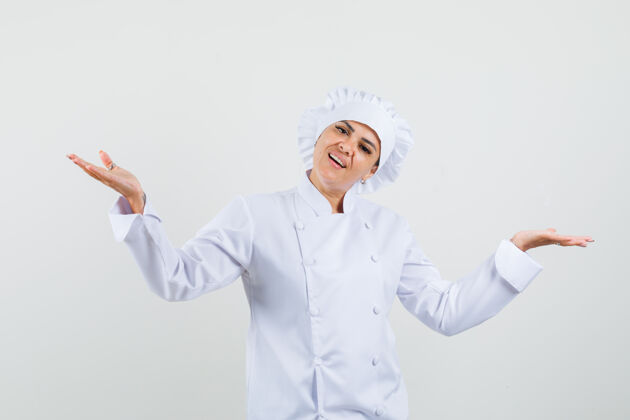工作穿着白色制服的女厨师做着秤的手势 看上去很高兴食品菜肴专业