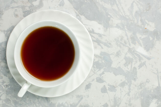 早晨在浅白色的桌子上俯瞰一杯热茶饮料杯子马克杯
