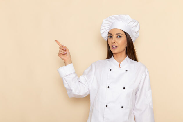 肖像身穿白色厨师服的年轻女厨师的正面图 在浅白的墙上抬起手指秘书女性专业