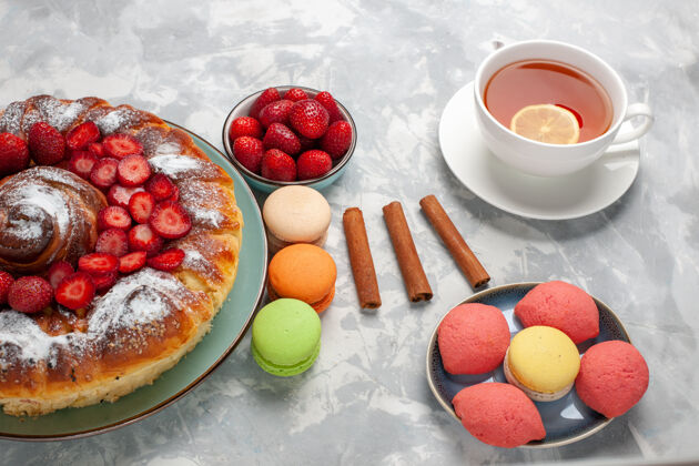 生的半俯视图美味的草莓派糖粉蛋糕 白色表面有麦卡龙和茶饮食半顶美味