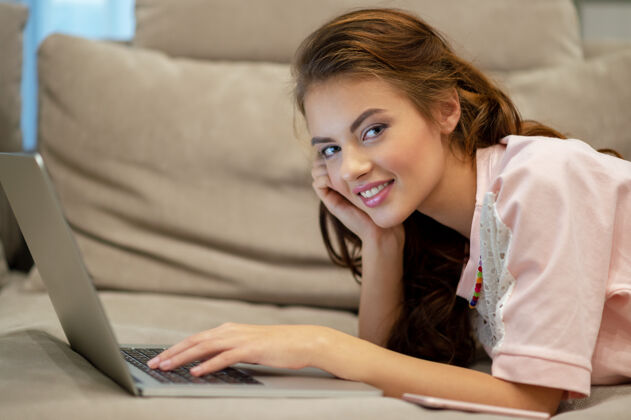 微笑漂亮的女人在家拿着笔记本电脑年轻的女人坐在家里用电脑工作享受在家的时光成人工作人