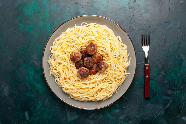 吃俯视图煮熟的意大利面食 深蓝色表面有肉丸球面团食物
