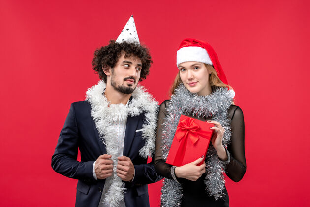 庆祝前视图年轻夫妇庆祝新年红墙圣诞爱情假期黑发年轻夫妇服装