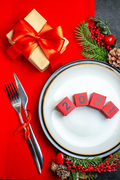 风景新年背景立面图 餐盘上有数字餐具套装装饰配件杉木树枝旁边有一个红色餐巾上的礼物号码冷杉水桶