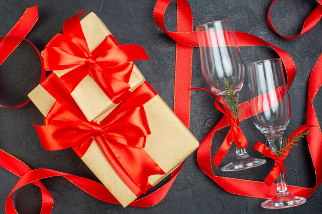 圣诞节美丽的礼物和玻璃酒杯在黑暗的背景俯视图包装视图高脚杯