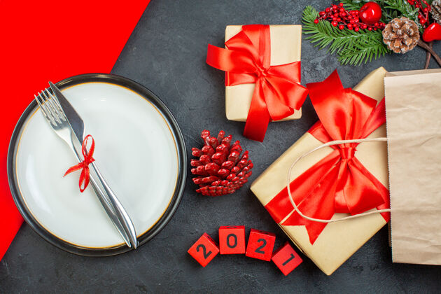 树枝上图美丽的礼物和餐具放在一个板上针叶树圆锥形冷杉枝数在一个黑暗的桌子上圣诞节餐具盘子