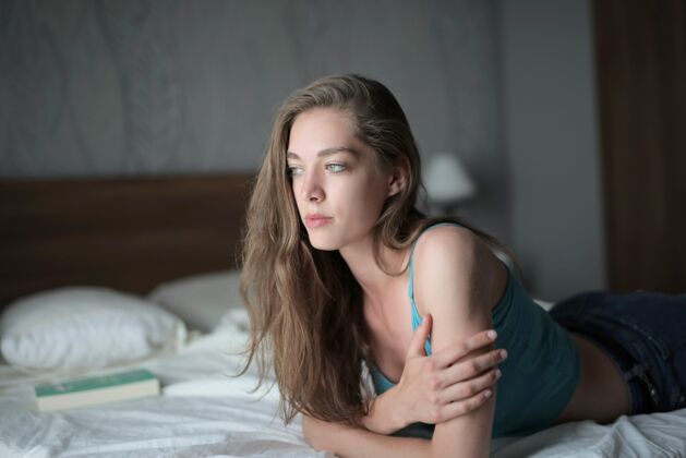 休息漂亮的年轻女性 留着长发 躺在房间灯光下的床上放松女士体贴