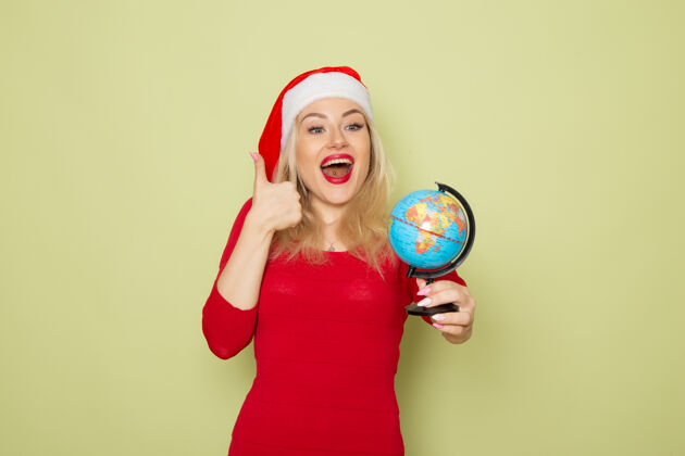成人正面图美丽的女性手持小地球仪在绿色的墙上节日情感圣诞新年雪的颜色气球观点小