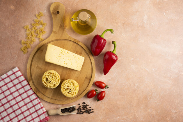 木板生的意大利面巢和奶酪放在木板上和蔬菜一起通心粉顶部视图食物