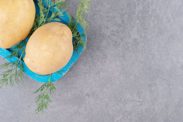 可食用一块蓝色的木板 上面放着生土豆和新鲜莳萝绿色香草吃