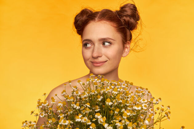 年轻十几岁的女孩 快乐的红发女人 带着两个发髻发型捧着一束野花 微笑着看着左边黄色墙壁上的复制空间特写成人红发长相