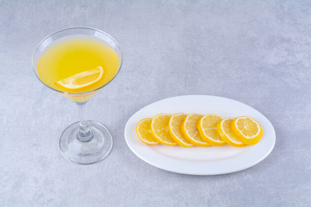 玻璃杯把柠檬片放在盘子里 旁边放一杯橙汁 放在大理石桌上切片维生素风味
