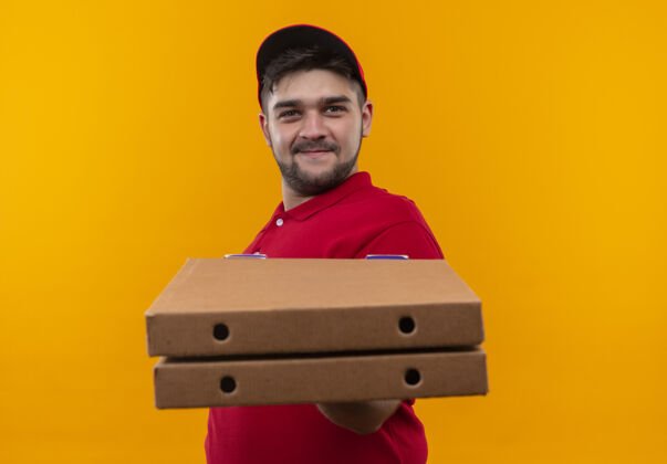 盒子身穿红色制服 头戴鸭舌帽的年轻送货员展示着一叠比萨饼盒 自信地微笑着微笑男人堆叠