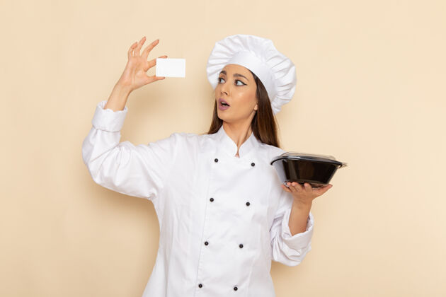 女性身穿白色厨师服的年轻女厨师在白色墙壁上拿着平底锅的正视图年轻人微笑前面