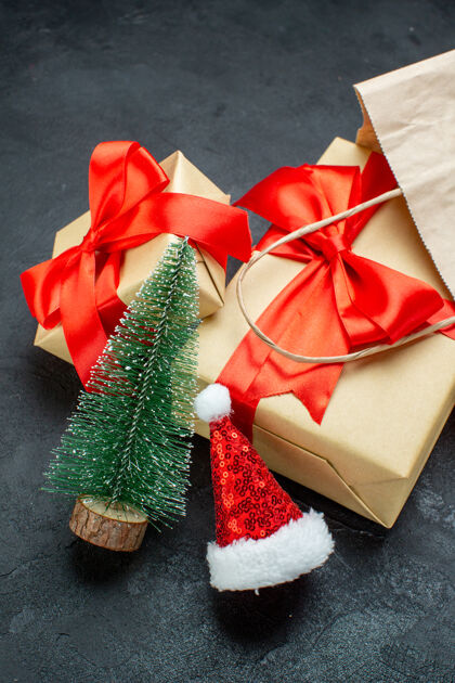 圣诞节黑色桌子上的红色丝带和圣诞树圣诞老人帽子的美丽礼物的垂直视图风景蝴蝶结轮子