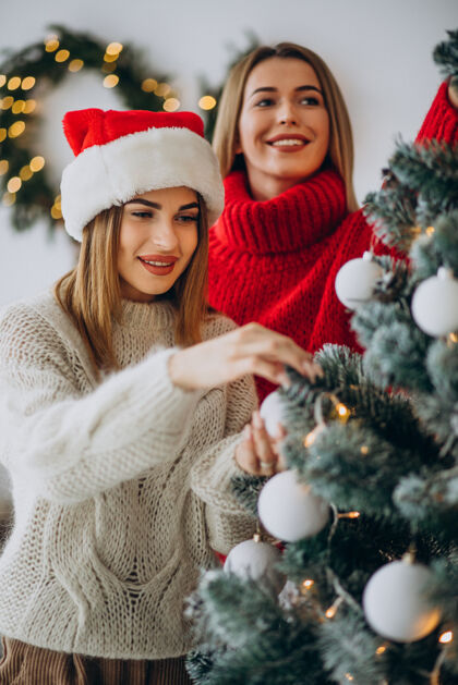 欢呼两个女孩在圣诞树旁交朋友漂亮盒子积极