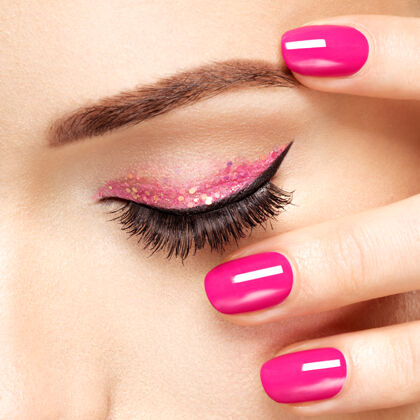 化妆特写镜头：眼睛附近有粉色指甲的女人的脸粉色指甲的指甲风格女人睫毛