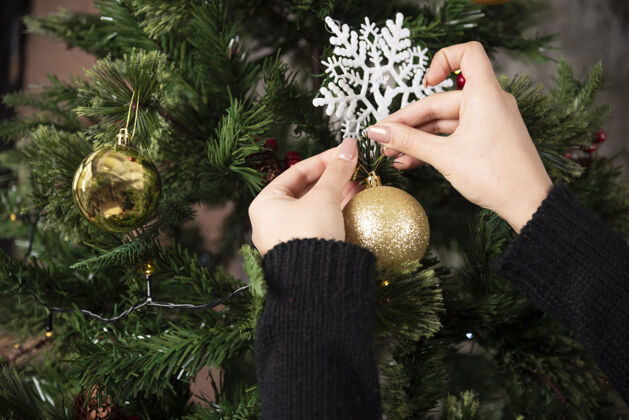 节日挂在圣诞树上的圣诞球的女人的手高品质的照片女孩家女人