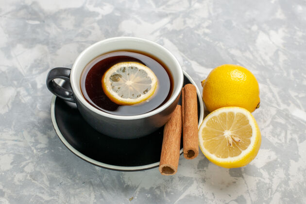 杯子正面是一杯茶 白色表面有肉桂和柠檬饮料柠檬水果