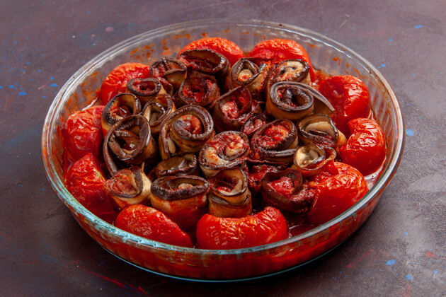 盘子前视图熟蔬菜餐番茄和茄子在黑暗的表面茄子生的西红柿