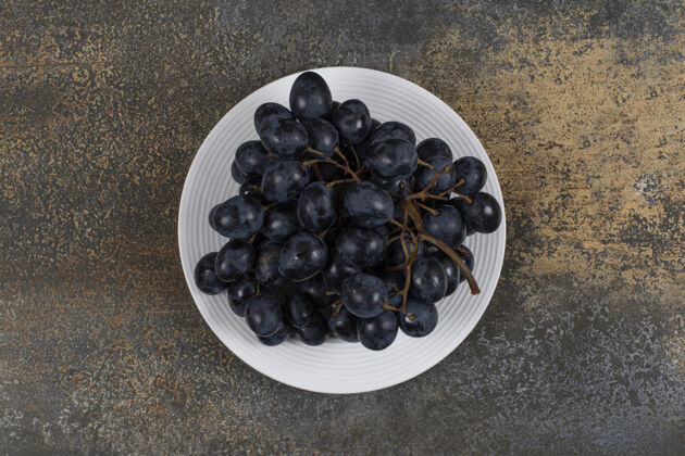 自然白色盘子上的一簇黑葡萄食用葡萄浆果