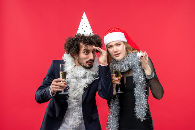 服装正面图年轻幸福的夫妇在红墙上庆祝新年照片圣诞爱情成人庆祝微笑