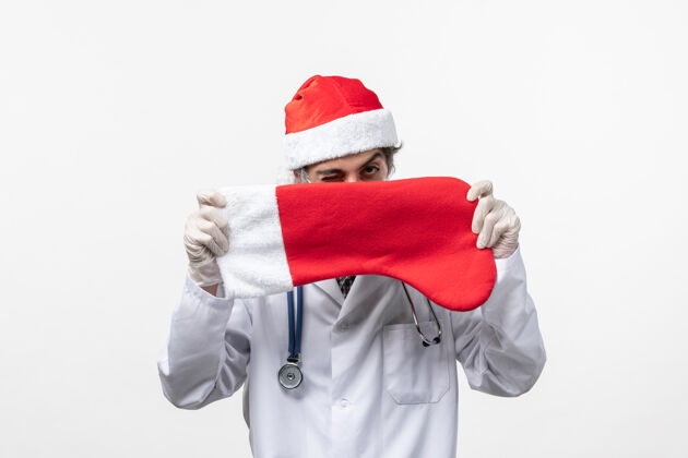 圣诞节正面图男医生举着白色墙壁上的大节日袜子病毒covid节日新年男医生快乐微笑