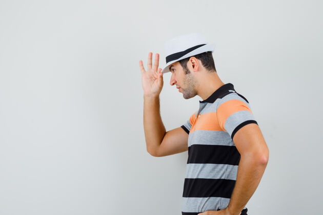 交叉一个穿着t恤 戴着帽子的年轻人用手指拿着帽子休闲手胡须