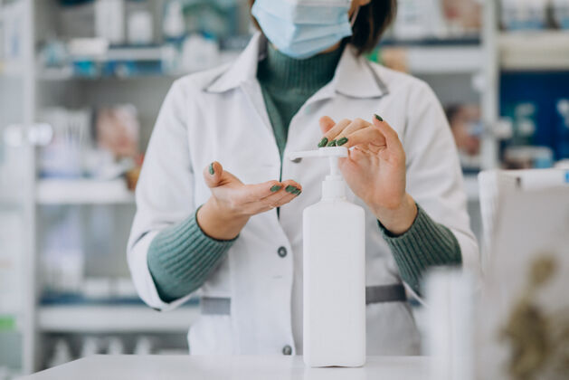 药品年轻的女药剂师用消毒剂洗手信心处方商店