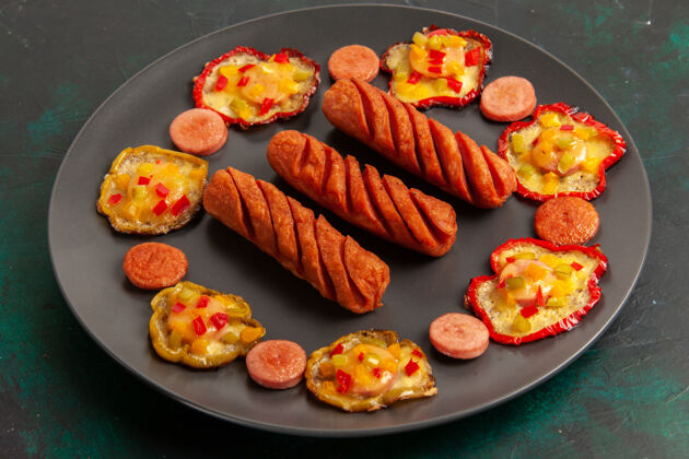 生的前视图煮熟的甜椒和香肠在黑暗的表面板内营养品寿司香肠