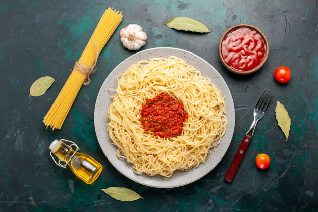 西红柿在深蓝色的桌子上俯瞰着意大利面和番茄肉末配料桌子酱汁