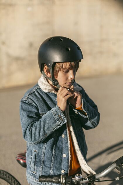 自行车男孩骑自行车前戴上安全帽的侧视图爱好活动乐趣